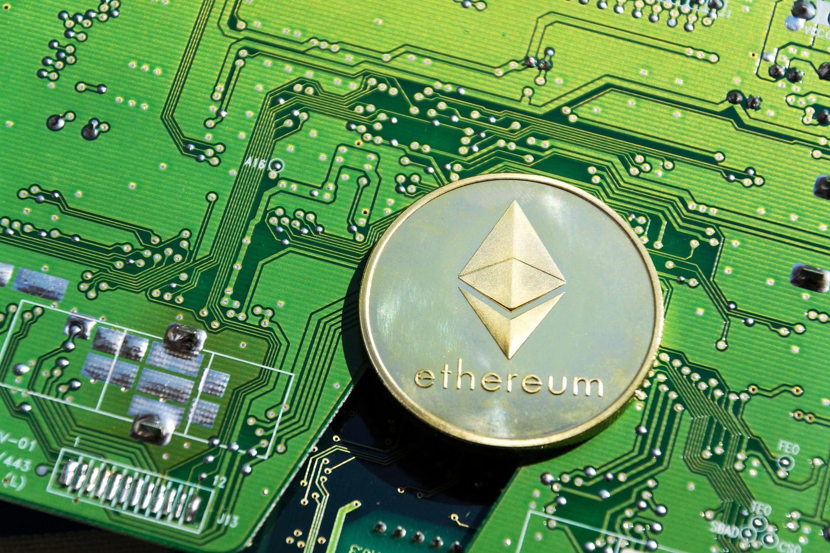 Golden Ethereum coin lying on computer motherboard, cryptocurrency investing, blockchain technology concept