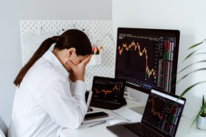 Frau vor Laptop mit fallenden Börsenkursen