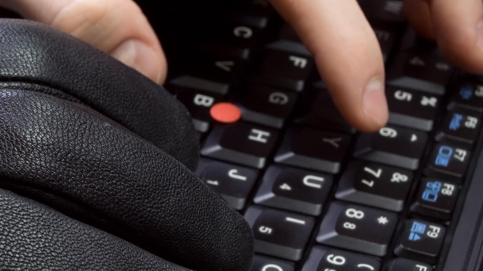 Hände auf Laptop Tastatur Schwarzer Handschuh